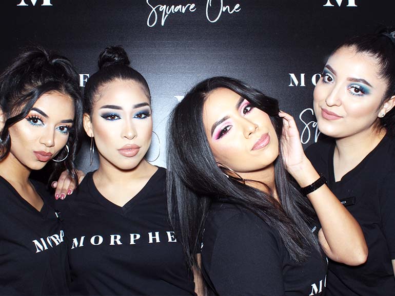 Four guests wearing custom branded MORPHE shirts posing together in front of a sleek black MORPHE at Square One photo booth backdrop during a corporate brand activation.
